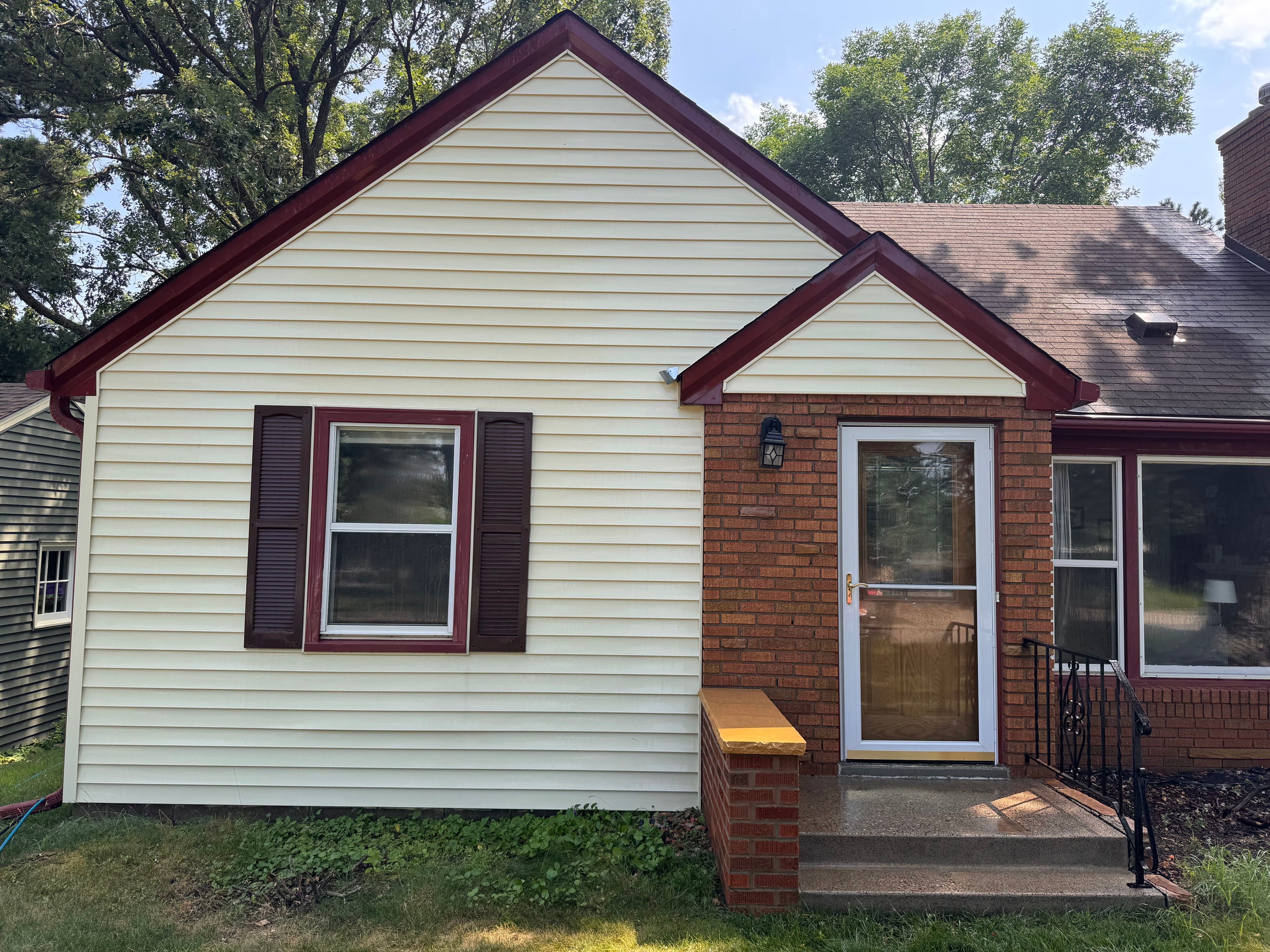 Front view of a charming house featuring red accents and a cozy porch.